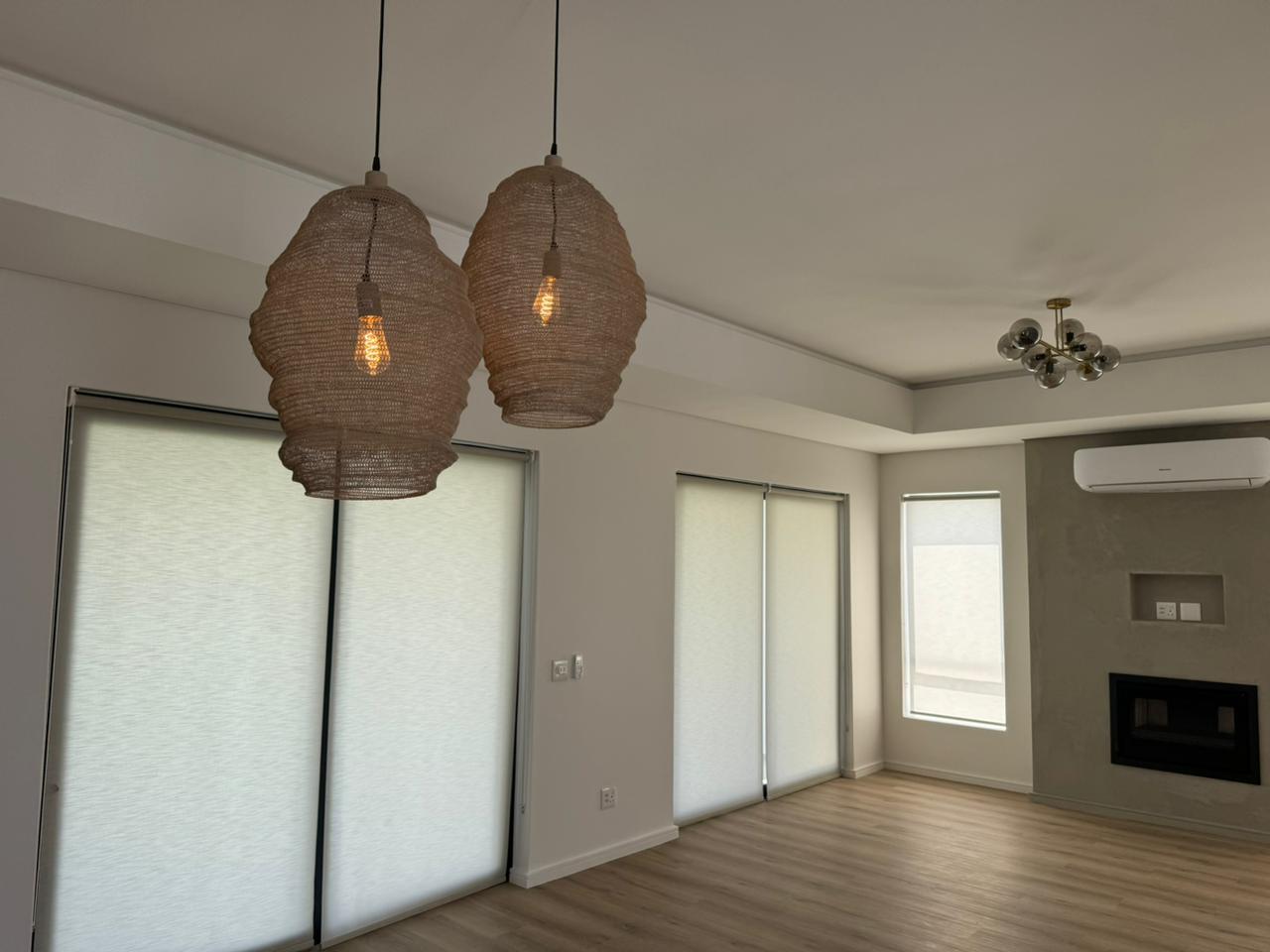 Open-plan lounge rattan pendants white rollers fireplace